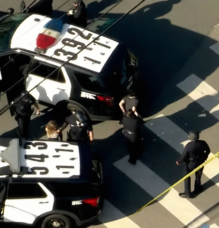 Police activity near patrol cars with crime scene tape, related to Weezer bassist and a manhunt incident in LA.