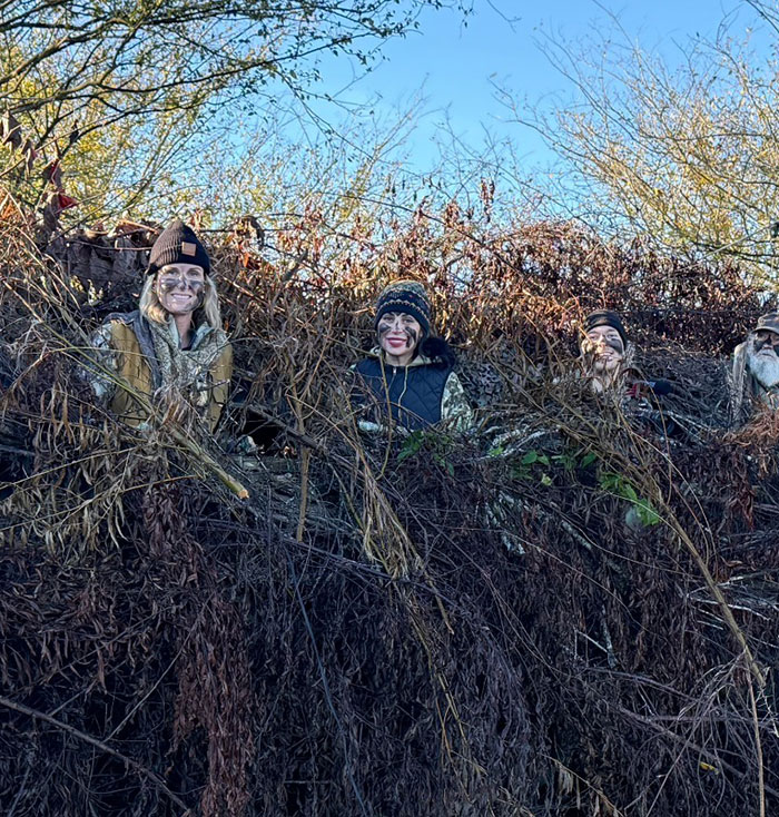 People camouflaged in foliage, participating in outdoor activities during daylight.
