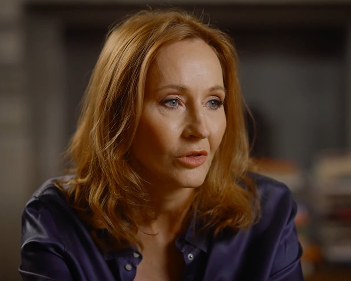 A woman with auburn hair speaking, focusing on the topic of trans allyship.