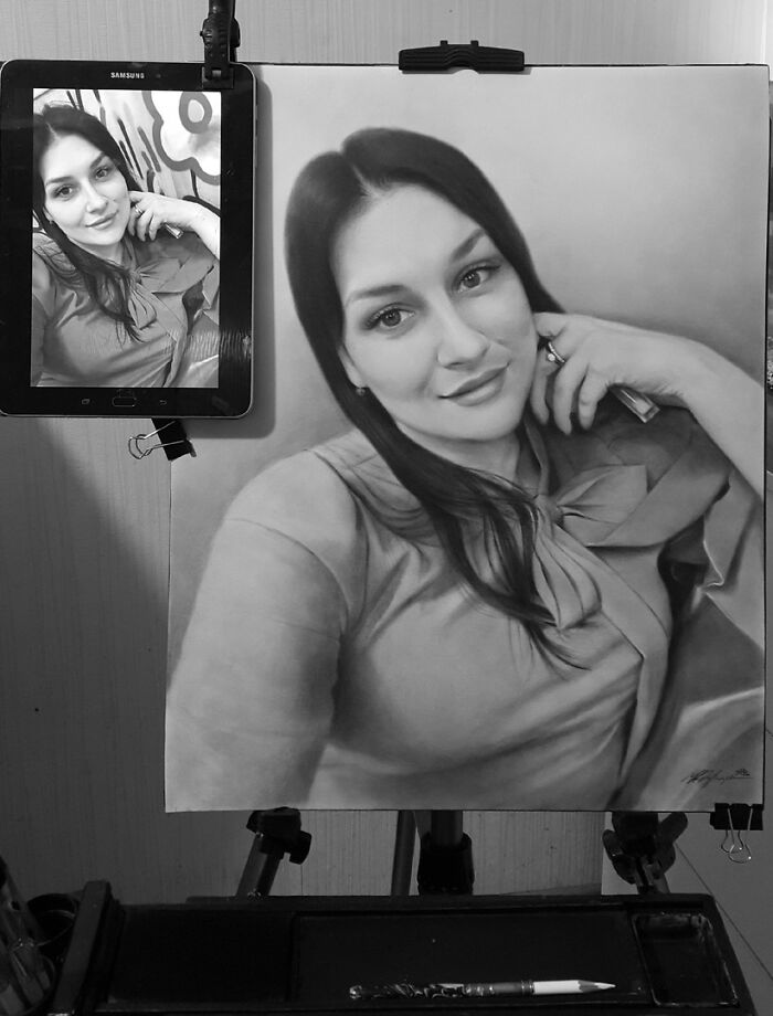 Hyper-realistic portrait drawing of a woman next to its reference photo on a tablet, showcasing pencil art skills.