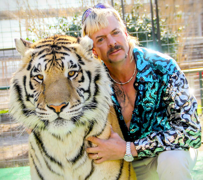 Man with a mullet in a shiny shirt posing with a tiger, reflecting 'Tiger King' star theme.