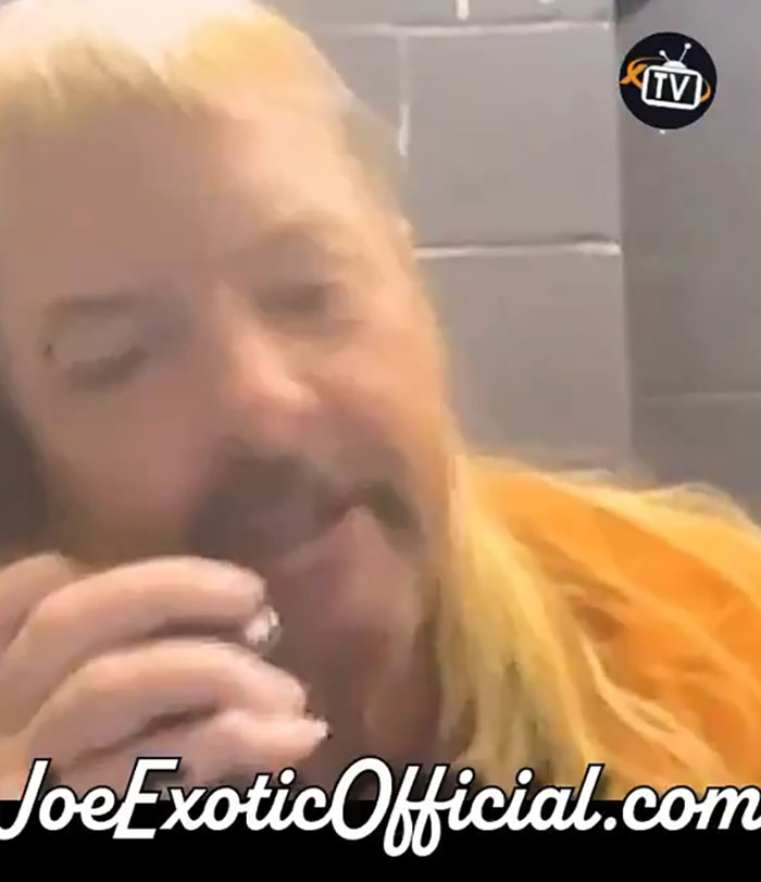 Joe Exotic in prison attire, speaking on a phone, image features JoeExoticOfficial.com branding.