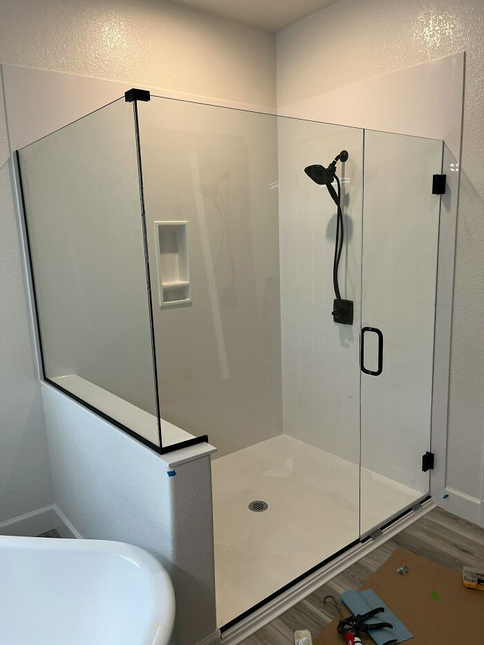 Modern shower enclosure with glass doors and black fixtures, illustrating impractical design aspects for some homes.