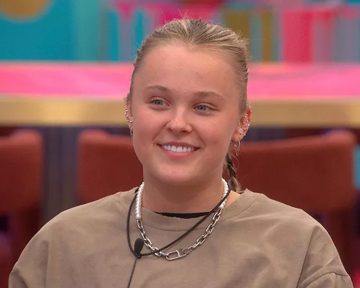 Young woman smiling, wearing casual clothes and ear piercings, amid "Dance Moms" and controversy discussions. Young woman smiling, wearing casual clothes and ear piercings, amid "Dance Moms" and controversy discussions.