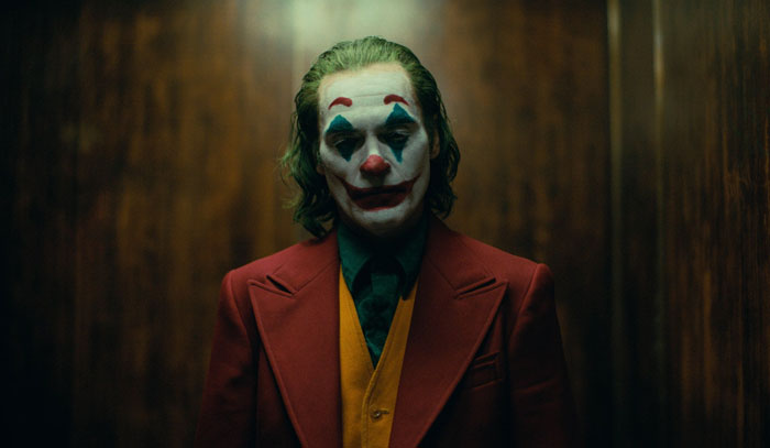 Actor in clown makeup and colorful suit portraying a difficult role, showcasing dedication and commitment to acting craft.