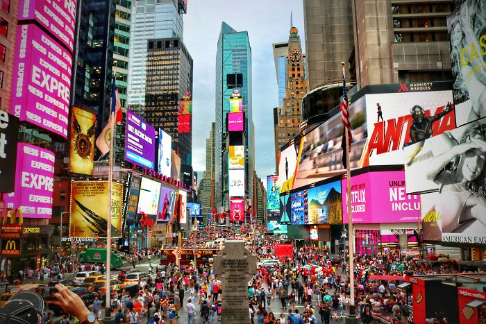 Crowded Times Square bustling with tourists, featuring bright billboards and skyscrapers, a classic FOMO tourist experience.