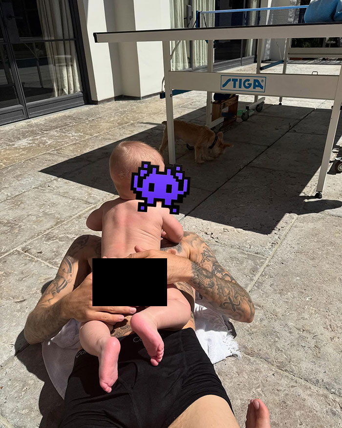 Baby by the pool with tattoos visible, creating online debate over photo privacy.