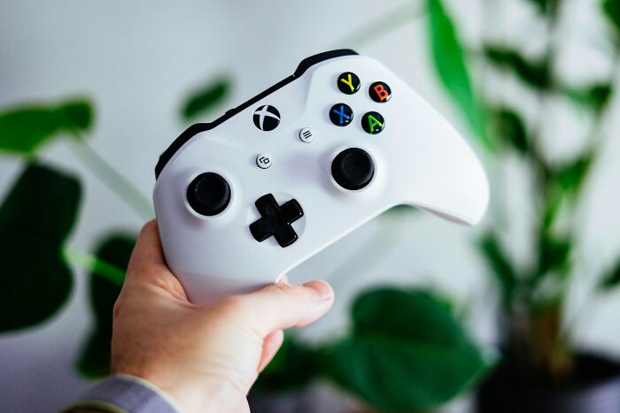 Hand holding a white gaming controller, illustrating a potential gaming loophole exploit.