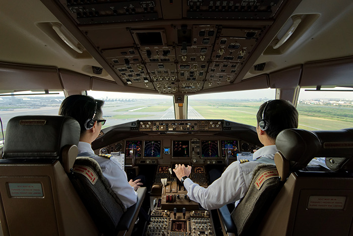 Two airline pilots in cockpit preparing for takeoff with flight delay disruption and crew intervention context.