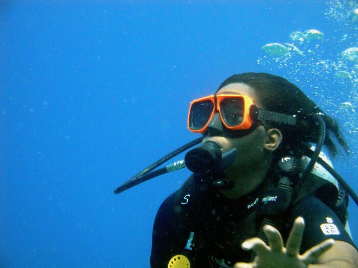 Diver underwater wearing orange goggles, exemplifying a disappointing FOMO experience among tourists.