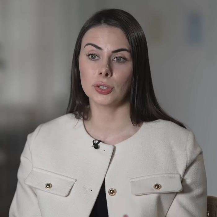 Woman in a white jacket speaking into a microphone, related to Leonardo DiCaprio's influencer ex documentary.