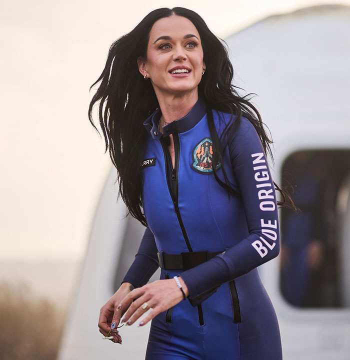 Singer in a Blue Origin suit, smiling and outdoors.