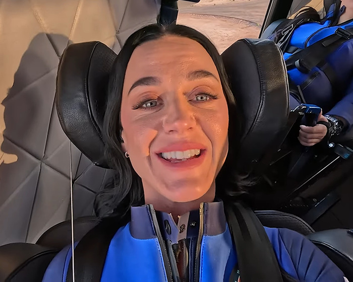 Person smiling in Blue Origin spacecraft seat, wearing a blue suit, ready for a suborbital adventure.