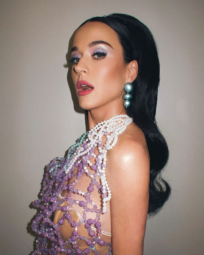 Katy Perry posing in beaded outfit and bold earrings, related to Blue Origin space flight critics controversy.