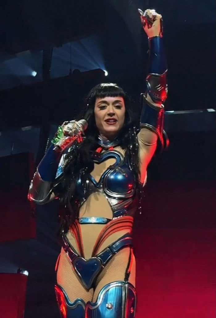 Singer performing on stage in a space-themed costume, showcasing unique "mom moves" during a tour debut.