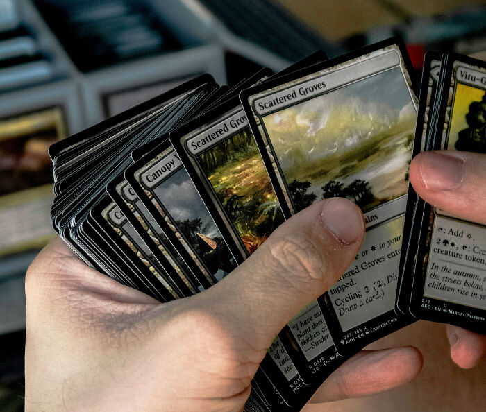 Person holding a fan of trading cards, illustrating relationship arguments that are so ridiculous they seem like sitcom material.