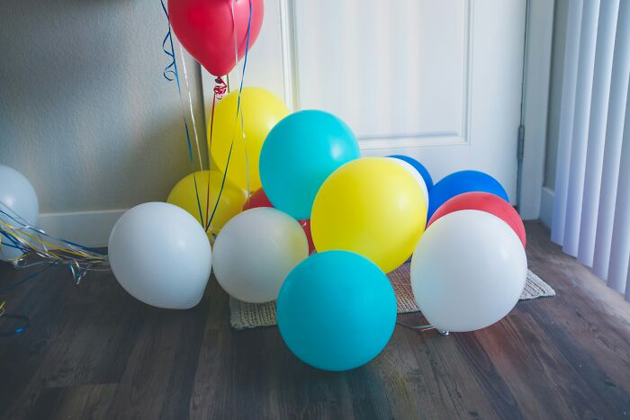 Colorful balloons on wooden floor, highlighting the hidden dangers of everyday objects.