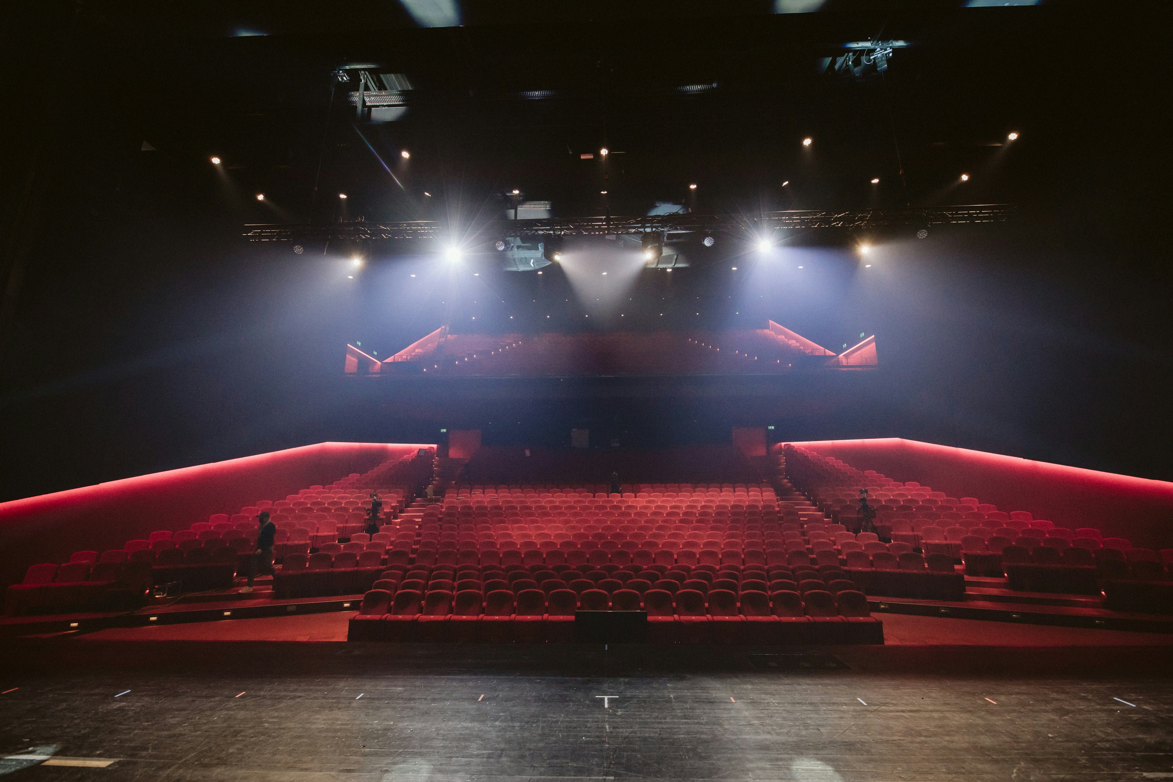 Event manager on stage at an empty theater with dramatic lighting.