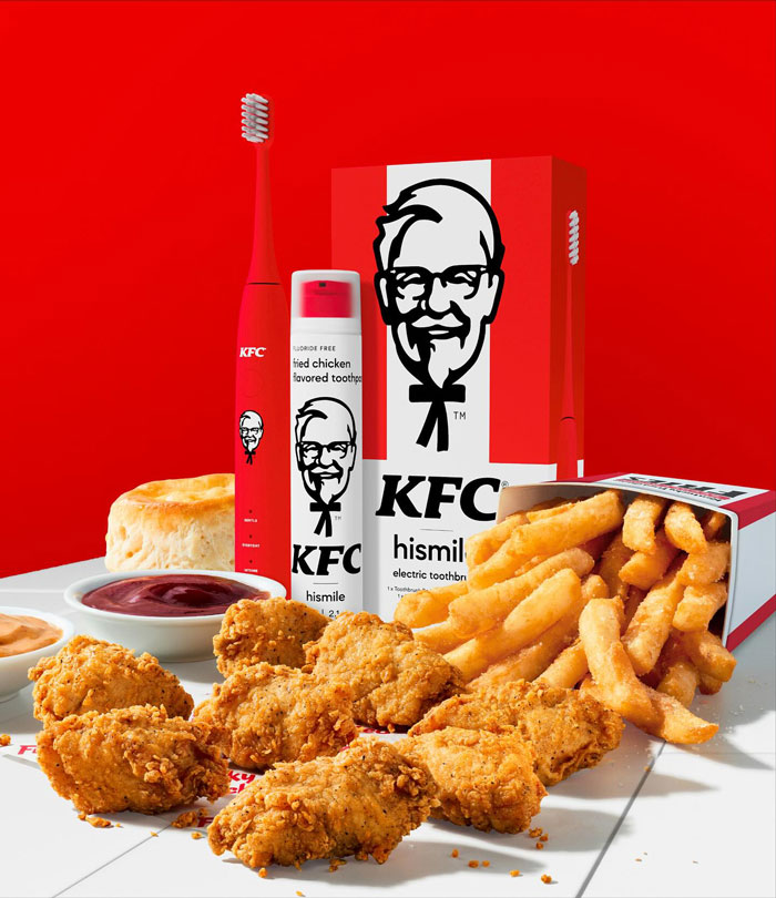 KFC toothpaste with 11 herbs and spices flavor, alongside fried chicken, fries, sauces, and biscuit in a vivid red setting.