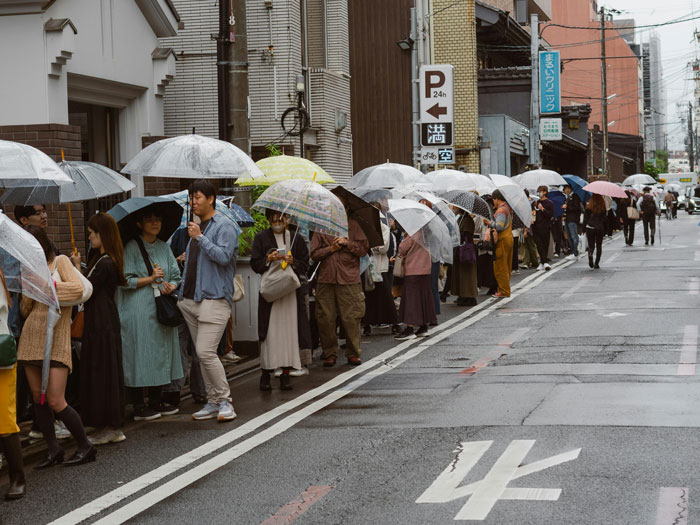 People standing in line with umbrellas, possibly waiting for the new KFC 'finger-licking' toothpaste.
