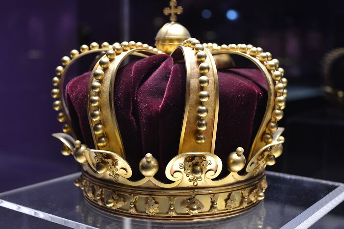 Golden royal crown with velvet cushion, representing monarchy.
