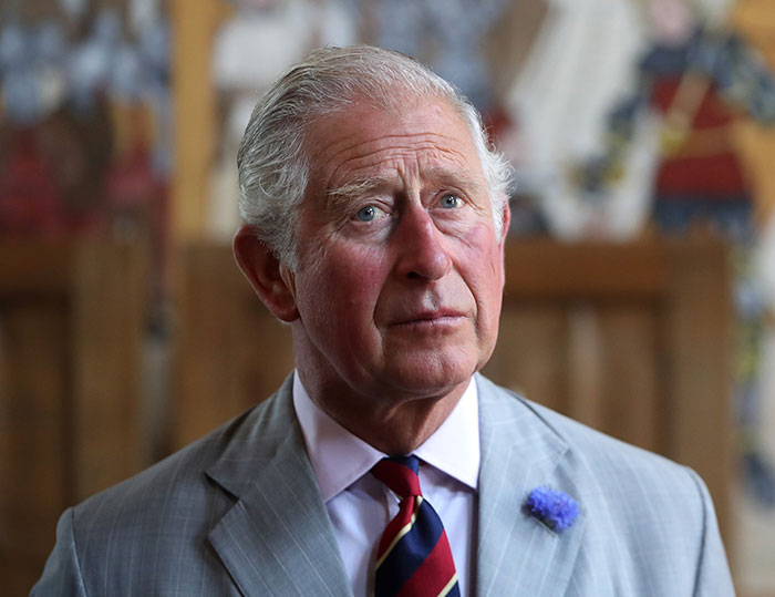 Man in a suit with a patterned tie, looking upward indoors.