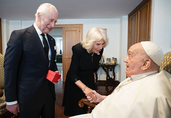 A man and woman greeting a religious leader in a formal setting, focusing on royal relations with the pope.