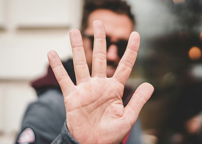 Person holding up hand, blocking view, symbolizing boundaries on money and bachelorette costs.