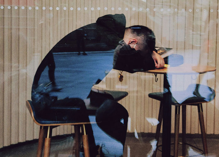 Person sitting at a desk, head down, pondering money boundaries and bachelorette costs.