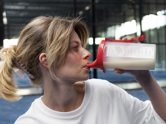 Woman drinking a protein shake, promoting the Switch-On Diet known for fat loss and muscle maintenance results.