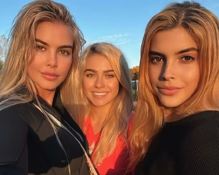 Three women with long hair smiling outdoors at sunset, related to DiCaprio's influencer ex documentary scandal.