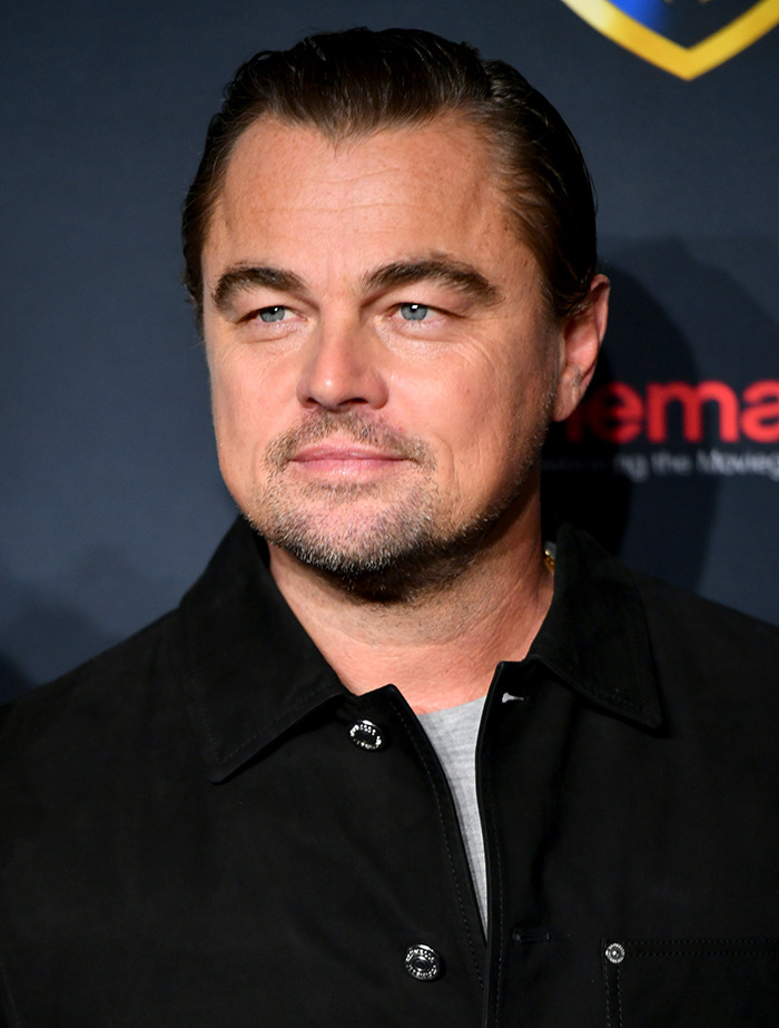 I don't know who's in the image. A person in a black jacket at an event promoting a documentary related to an influencer scandal.