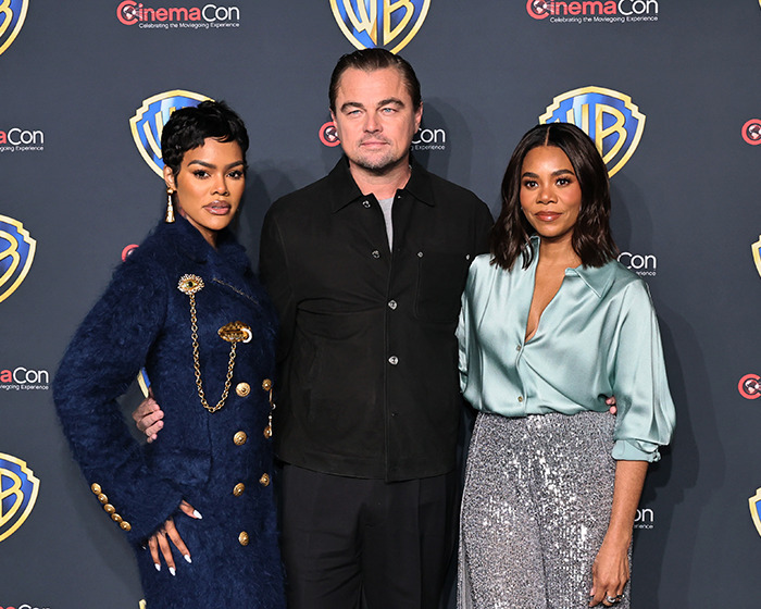 Leonardo DiCaprio on Las Vegas red carpet, showcasing new look with two women at a CinemaCon event.