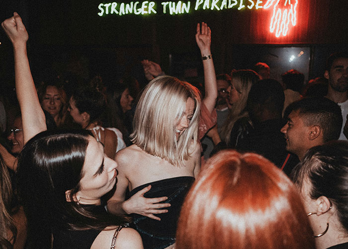 Group of people partying under neon lights, potentially highlighting lifestyle red flags.