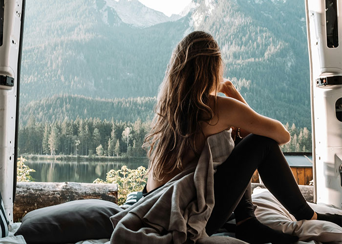 Woman in a van looking at a scenic mountain view, symbolizing lifestyle choices and potential red flags.