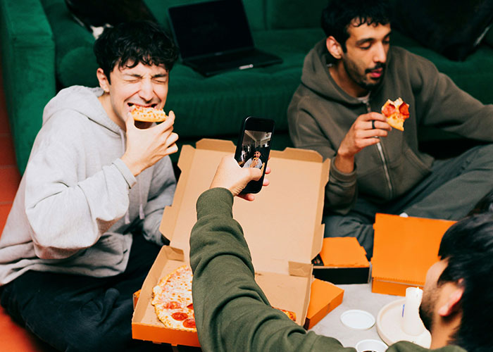 Friends eating pizza together, capturing a moment, highlighting lifestyle choices and potential red flags.