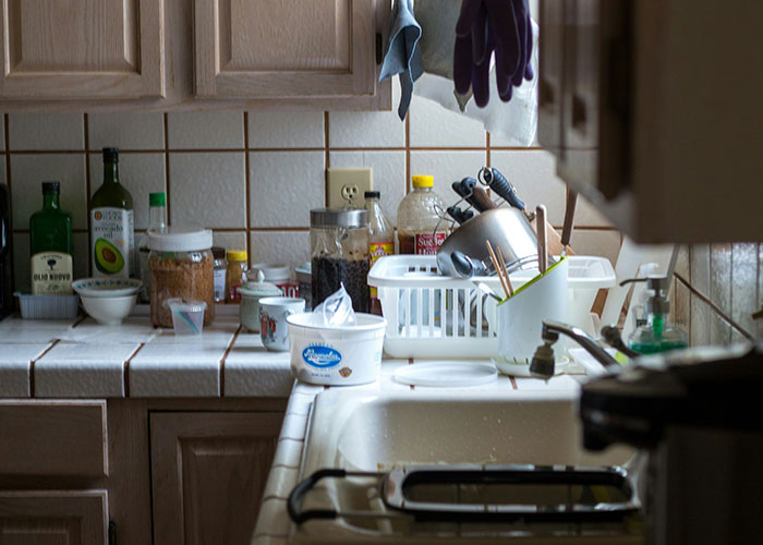 Cluttered kitchen counter with dishes and condiments, highlighting lifestyle choices that scream red flag.