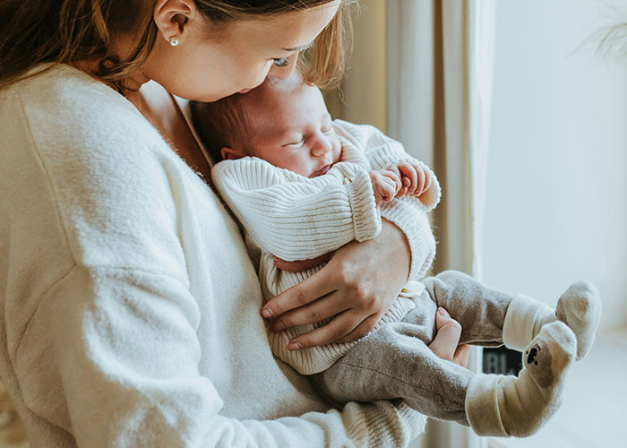 A woman lovingly cradling a newborn, highlighting lifestyle choices and potential red flags.