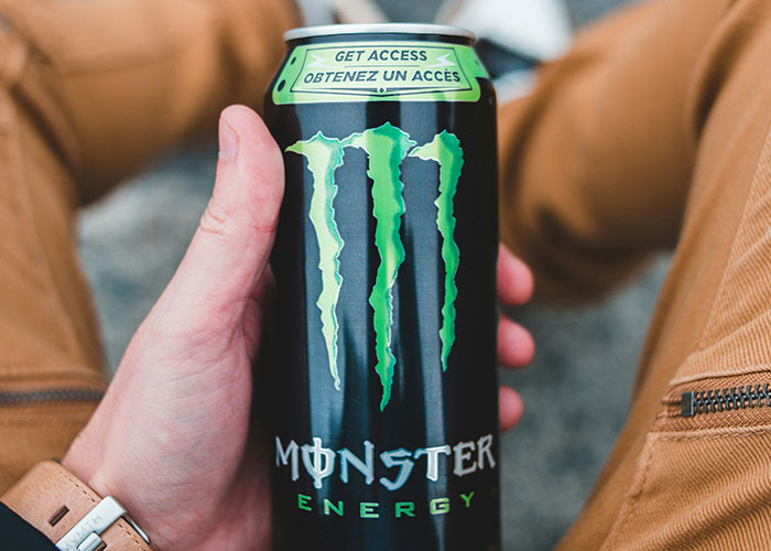 Person holding a can of Monster Energy drink, a lifestyle choice often seen as a red flag.