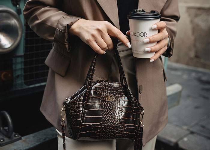 Person with coffee wearing a brown coat, holding a purse, illustrating lifestyle choices and potential red flags.