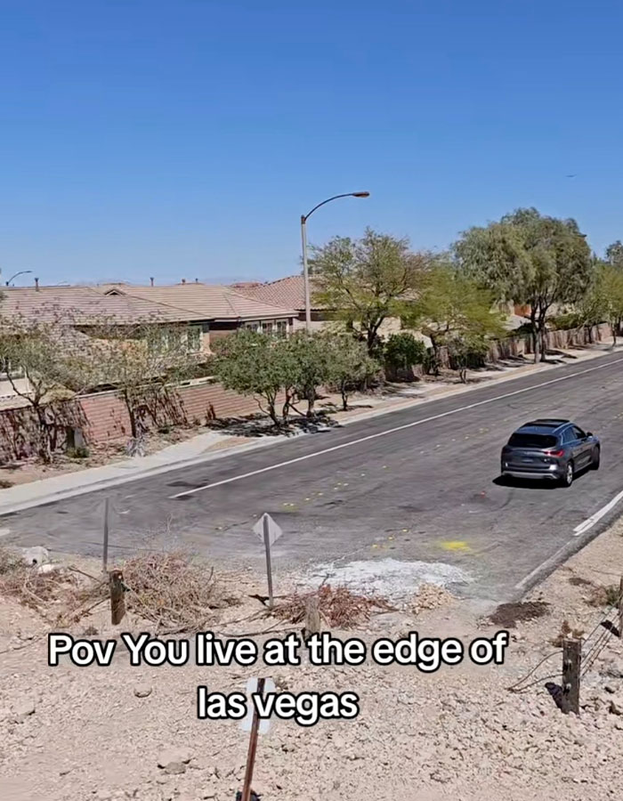 Car on a desert road at the edge of Las Vegas, bordered by residential houses and desert terrain.