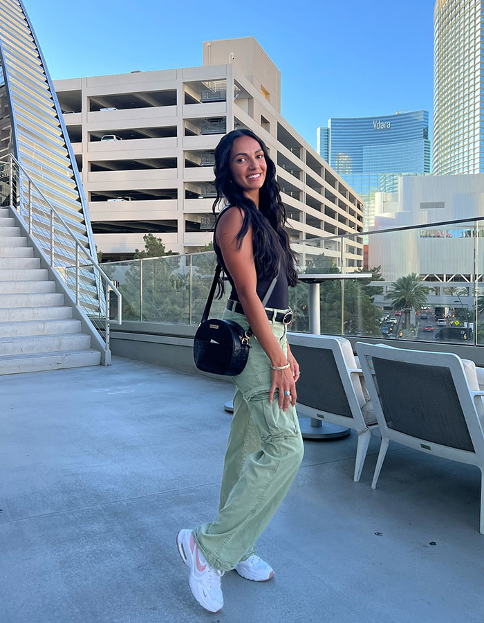 Smiling woman on a Vegas rooftop, showcasing city skyline and modern architecture.