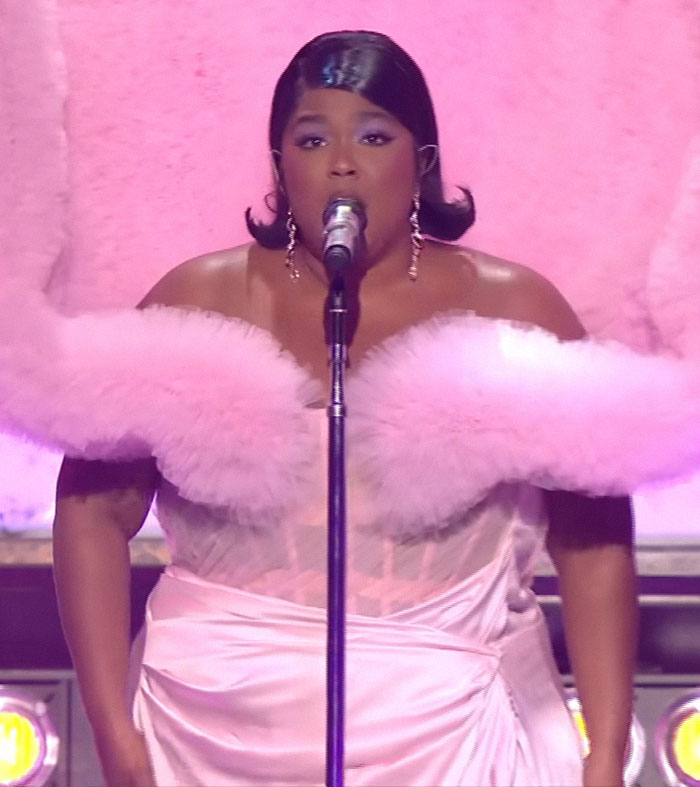 Singer performing on stage in a pink outfit, sparking outrage with remarks about Britney Spears and Janet Jackson.