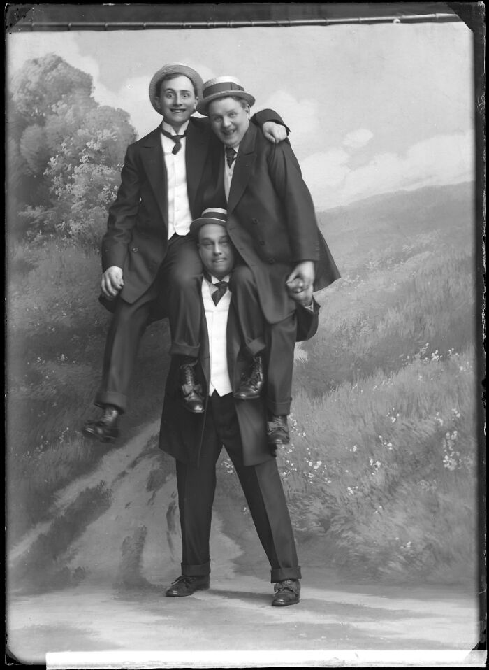 Three men in vintage suits and hats posing playfully in a rare photograph rescued from glass negatives.