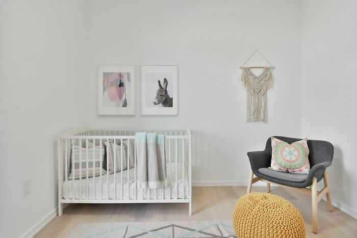 Minimalist nursery room with a crib, chair, and wall art; highlights unique home decor style.