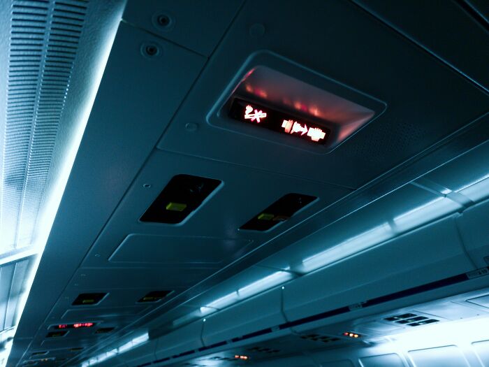 Airplane overhead console with lit seatbelt and no smoking signs, evoking memories of adult tantrums in-flight.
