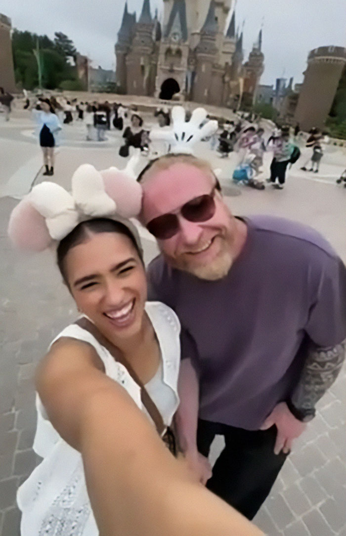 Couple smiling on vacation in front of a castle.
