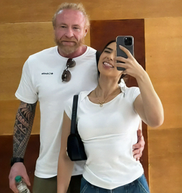 Man on vacation with wife, both smiling, capturing a selfie together.