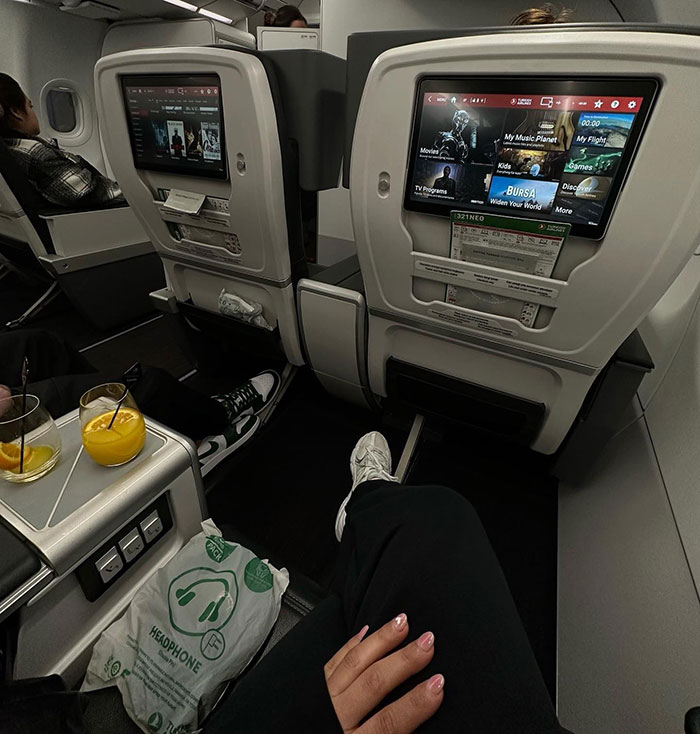 Airplane cabin with screens and drinks, related to a family's search for a buried loved one.
