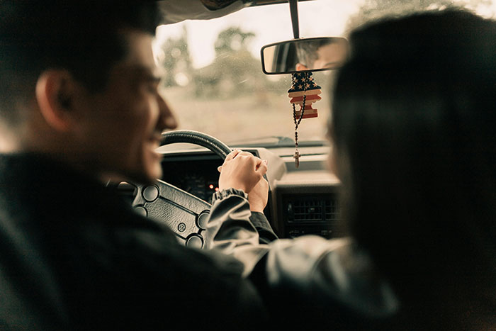Man and woman holding hands inside a car, symbolizing support amid statistics predicting pregnant friend will have a boy.